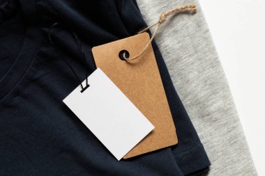 Tasarım için yakın plan olarak beyaz arkaplanda etiketleri olan iki gri ve mavi tişört.