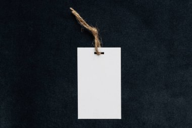 İpin üzerindeki beyaz boş etiket tasarım için bir model olarak koyu mavi tüylü kadife kumaşa uzanır.