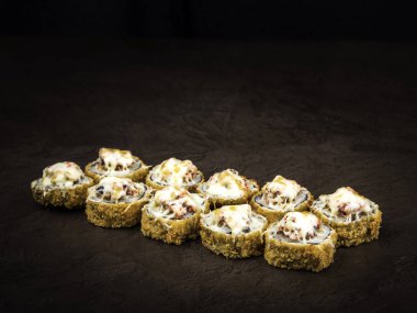 Japon tarzında peynir ile sıcak rulo kısmı, yan görünüm, koyu bir arka plan karşı.