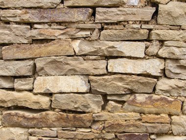 Doğal ışık altında sarı ve kahverengi taştan yapılmış yığma parçası, yakın çekim