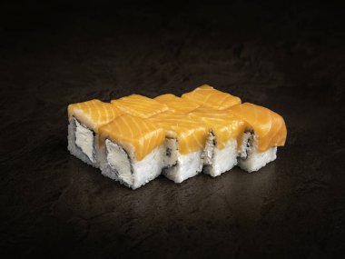 Karanlık bir arka planda yumuşak peynir ve alabalıkla Japon tarzı rulo parçaları