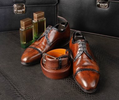 Fashionable men's shoes of brown color with two bottles of men's perfumes stand on a table covered with python skin clipart