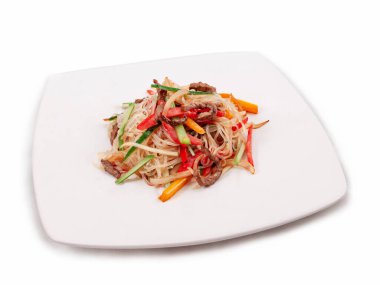 Kızarmış et ve sebzeli Asya usulü pirinç eriştesi. Kare bir tabakta. Yaklaş, yan görüş. Seçici odak