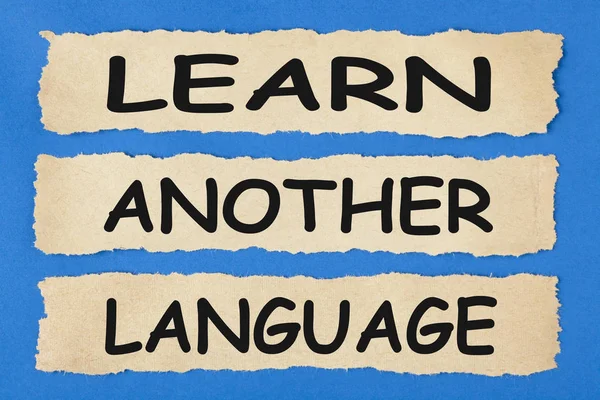 LEARN ANOTHER LANGUAGE written on old torn paper on blue background. Business concept.