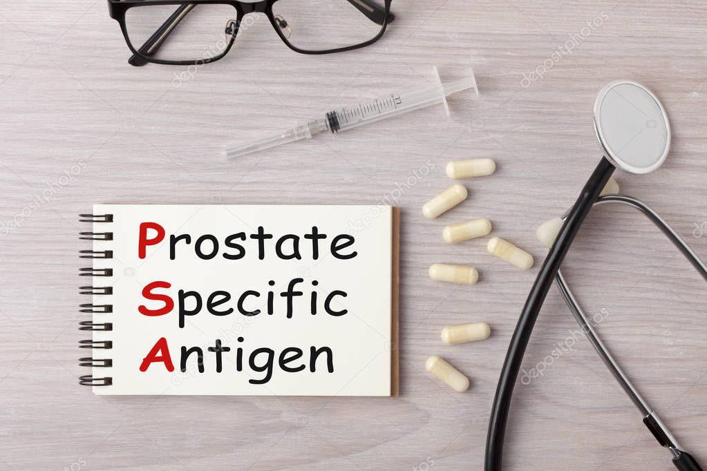 Prostate-Specific Antigen (PSA) written on notebook with stethoscope, syringe, eyeglasses and pills. Medical acronym concept.
