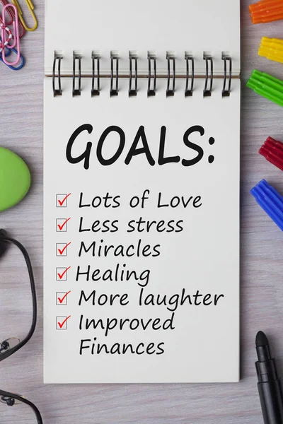 Pen marker ve ahşap masa üzerine gözlük ile defter üzerinde yazılı gol.