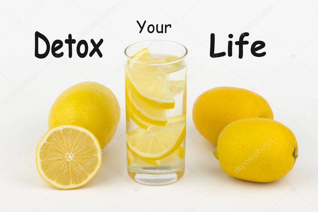 Detox Your Life written on white background and glass of water with lemon slices.