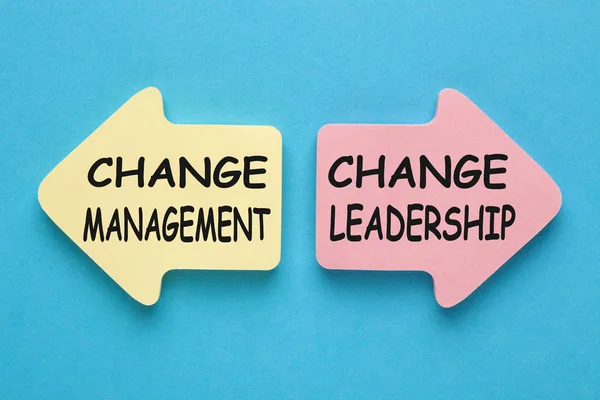 Change Management versus Change Leadership written on paper arrows on blue background. Business concept.