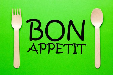 Kaşık ve çatal yeşil zemin üzerine metin afiyet olsun.