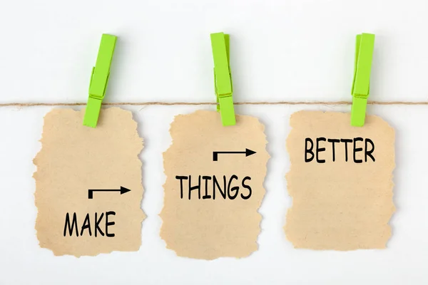 Make Things Better written on old torn paper with clip hanging on white background. Improvement Concept.