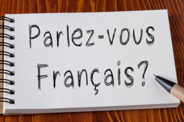 Yapmak sen Speak Fransız (Fransızca) soru ile kalem ahşap masa üzerinde bir kenara not defteri sayfa üzerinde yazılı.