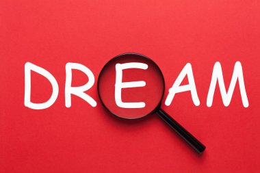 Kırmızı bir arka plan ve Büyüteç Camı yazılı rüya. İş kavramı.