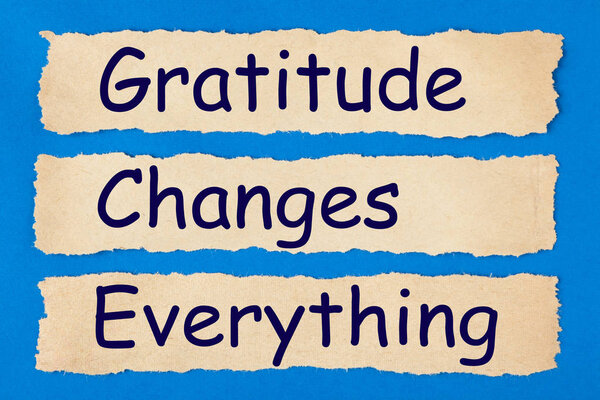 Gratitude Changes Everything written in old torn paper on blue background. Politeness, thanks, gratitude concept