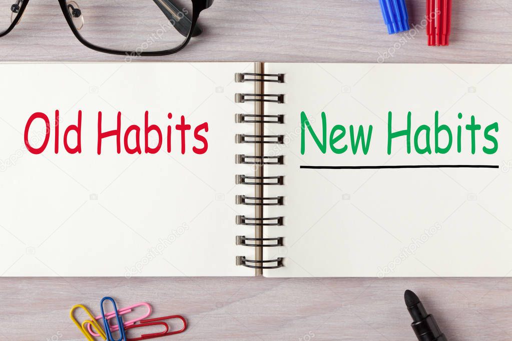 New Habits vs Old Habits written on open spiral notebook and various stationery. Business concept.