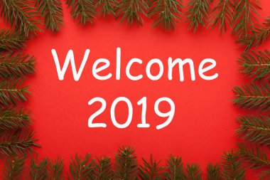 Çam dalları ve metin hoş geldiniz 2019 kırmızı zemin üzerine çerçeve. Yeni yıl kavramı