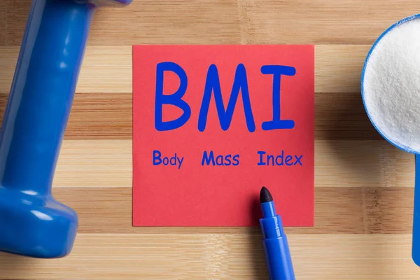 Body Mass Index (BMI) written on note and scoop with creatine and dumbbell. Concept sport, diet, fitness, healthy eating.