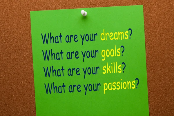 What are your dreams, goals, skills, and passions question on green paper sheet pinned on cork board. Business concept