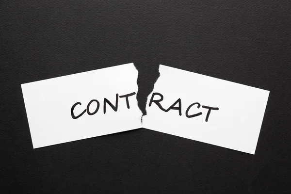 The word contract on torn paper in black background.