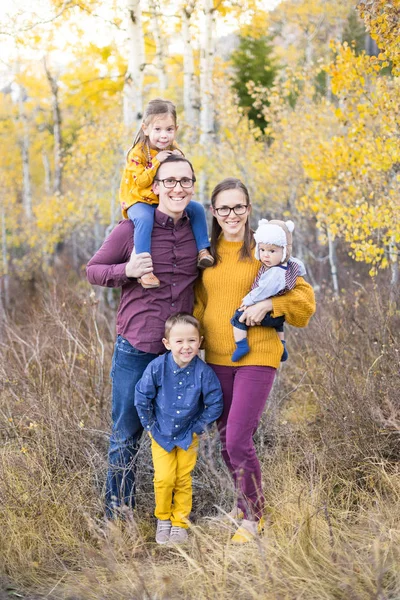 Sarı yapraklı kavak ağacı olan bir dağda aile portresi.