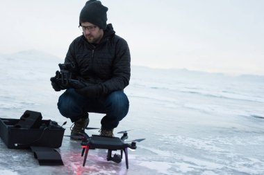 Adam donmuş göl üzerinde siyah drone helikopter uçar