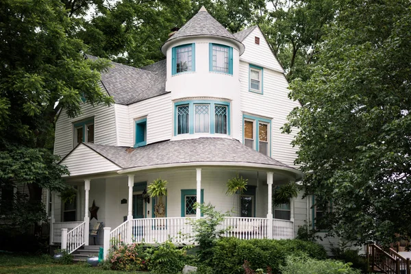 White home with large porch in forested area