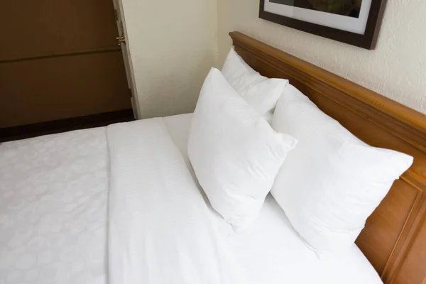 Clean, made bed with white linens and pillows