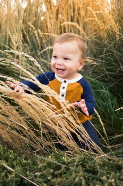 Tatlı çocuk poz veriyor ve uzun süs çimlerinde gülümsüyor.