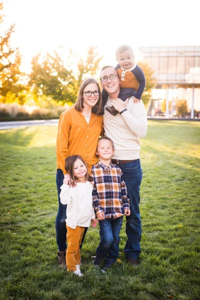 Young family of five take portraits at fall colored park