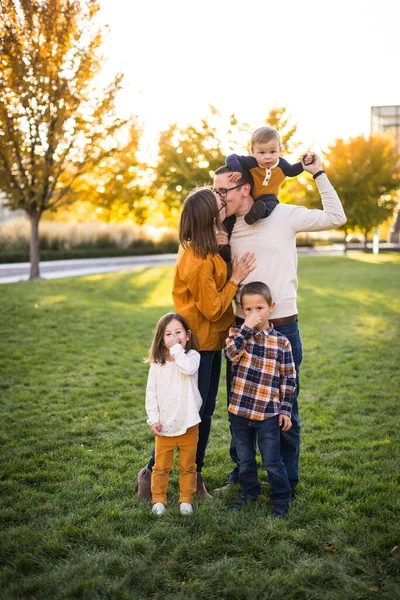 Young family of five take portraits at fall colored park