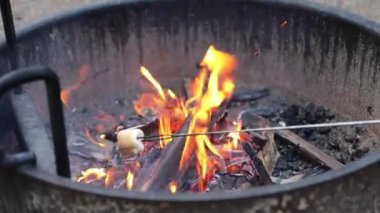 Sıcak ateş ışıkları, doğadaki kamp alanındaki metal ateş çemberinde yanan kamp ateşinden geliyor.