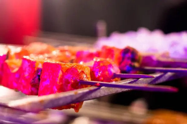 Paneer y carne tikka tostado en pinchos bajo luz de color — Foto de Stock