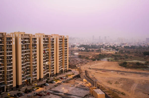 Хмарочоси в Гургаоні, що виходять на безплідну землю і село — стокове фото