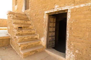 Sandstone buildings with stairs and low doors in Kumbalgarh Jaisalmer clipart