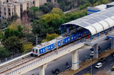 Yüksek bir metro istasyonuna gelen metro treninin havadan çekilmiş fotoğrafı 