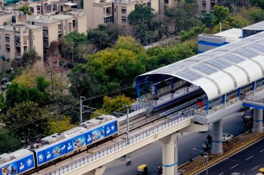 Yüksek bir metro istasyonuna gelen metro treninin havadan çekilmiş fotoğrafı 