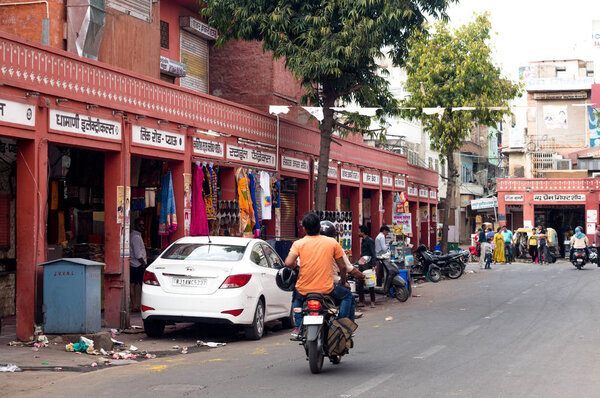 Люди, въезжающие на мотоцикле в пустой и закрытый рынок Джайпура
