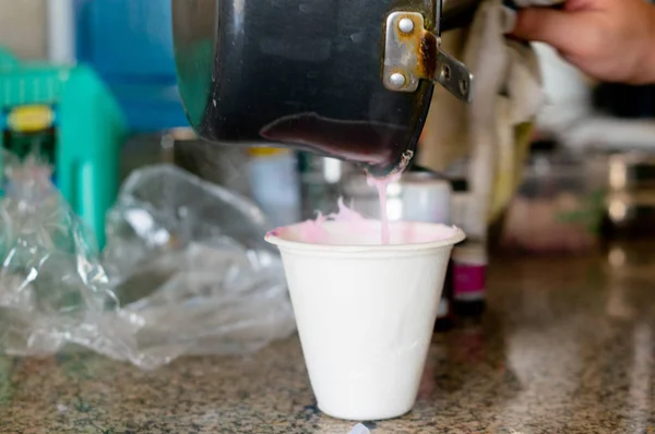 Molton soap base being poured from a black pan into a measuring cup