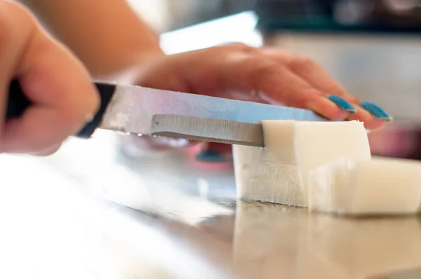 lady cutting cold process soap base into blocks for melting