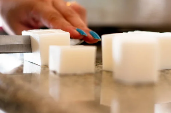 lady cutting cold process soap base into blocks for melting