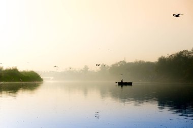 Early morning at yamuna ghat with golden sun, fog and blue water clipart