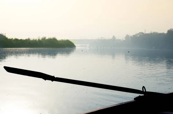 Silhuett av båten åra kommer ut ur vattnet med en dimmig flod i — Stockfoto