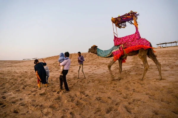 Turistas caminando hasta un camello en la playa para dar un paseo — Foto de Stock
