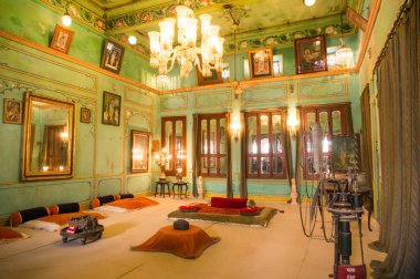Udaipur şehir sarayında kraliyet ailesi için avize, ışık ve zemin oturma ile yeşil duvarlı oda