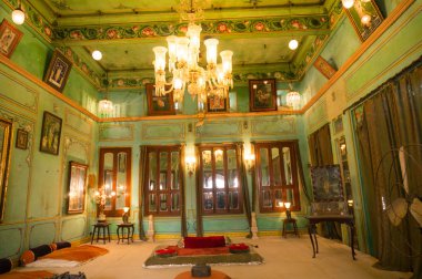 Udaipur şehir sarayında kraliyet ailesi için avize, ışık ve zemin oturma ile yeşil duvarlı oda