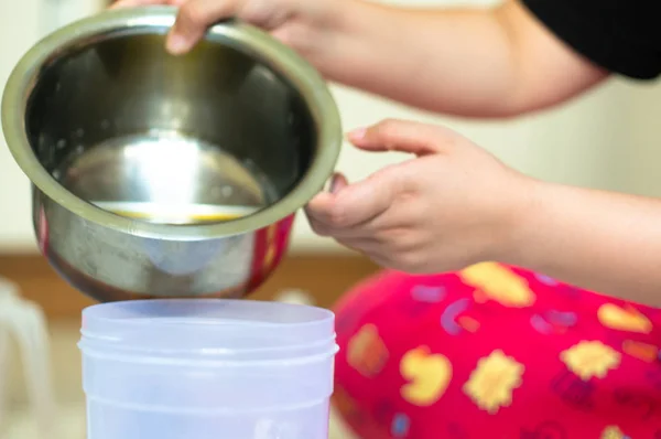 Pouring an oil mix from a steel container into a plastic container for cooking, soap making and home chemistry