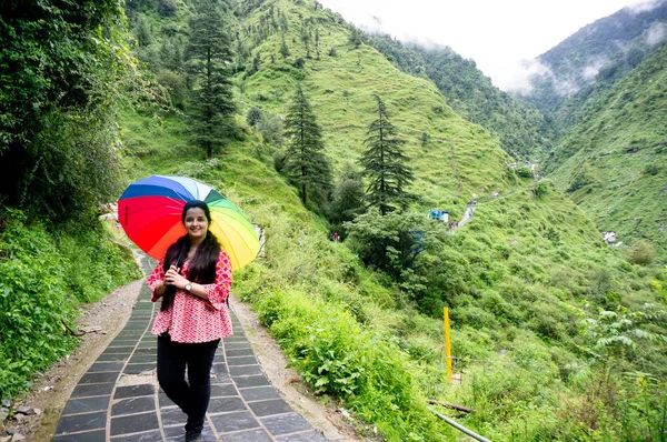 Joven chica india frente a la cámara con colorido paraguas en la planta cubierta de nubes colinas de niebla —  Fotos de Stock