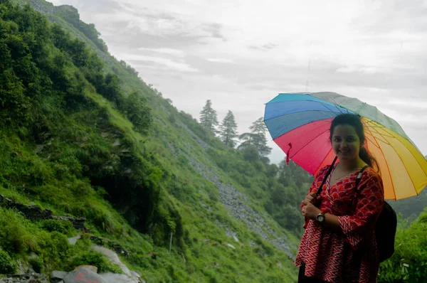 Młoda indyjska dziewczyna z kolorowym parasolem z roślinami pokrytymi wzgórzami za nią w Himachal Pradesh — Zdjęcie stockowe