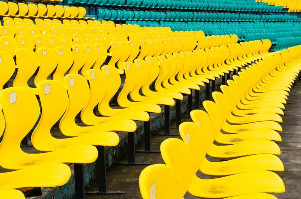 Leere gelbe Plastikstühle in symmetrischen Reihen in einem Cricketstadion — Stockfoto