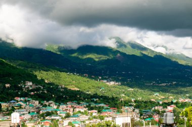 Hindistan 'daki tepe istasyonu binalar ve çimlerle kaplı tepeler üzerine bulutlar düşüyor.