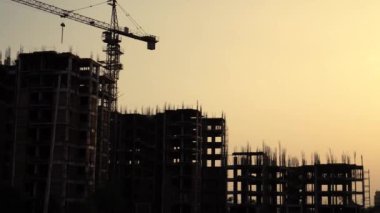 İnşaat halindeki binaların silüet görüntüleri, üzerinde vinç ve destek kirişleri var. Delhi, Hindistan 'da net bir şekilde görülüyor.